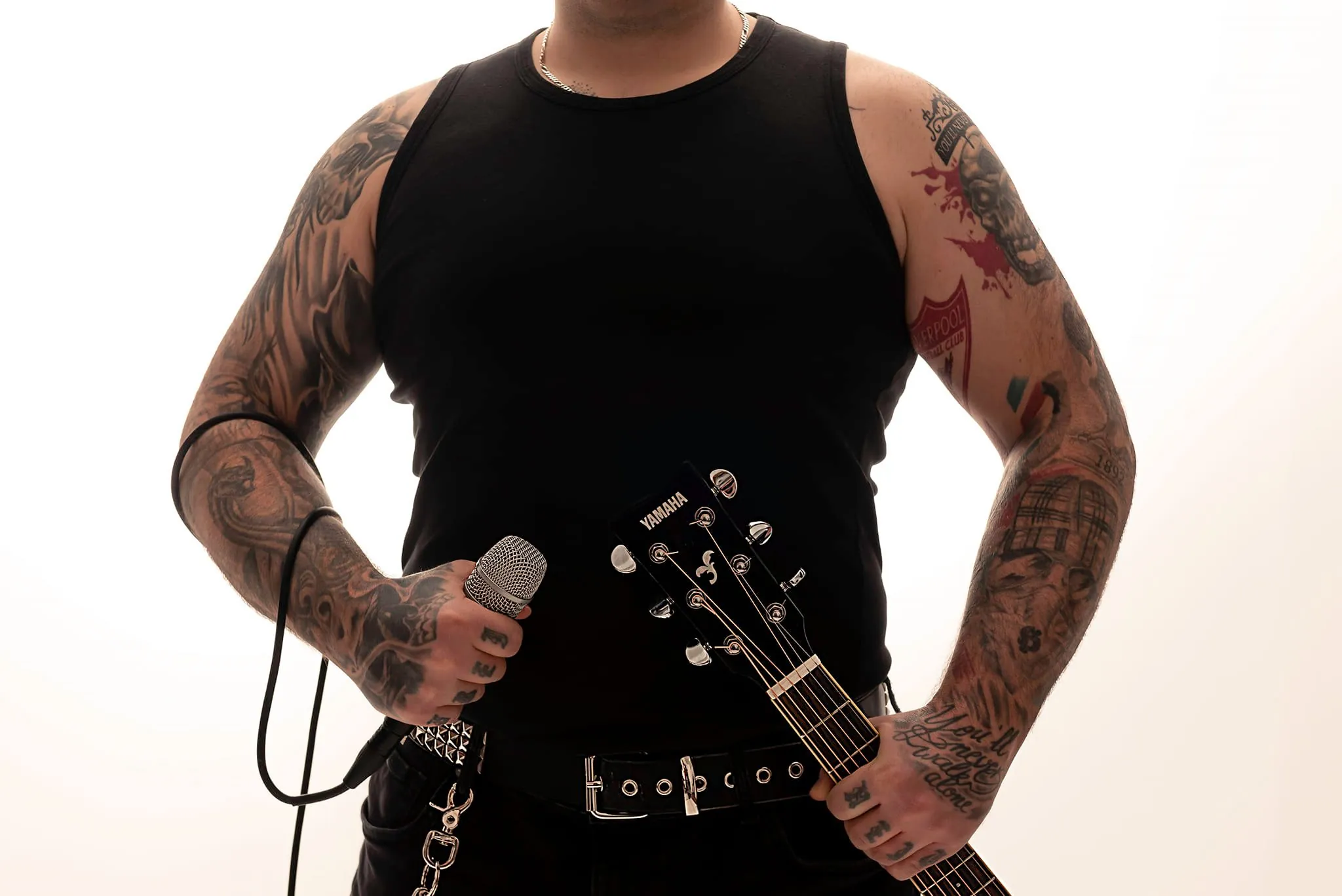 Tätowierte Arme von Ändie Clash mit E-Gitarre und Mikrofon